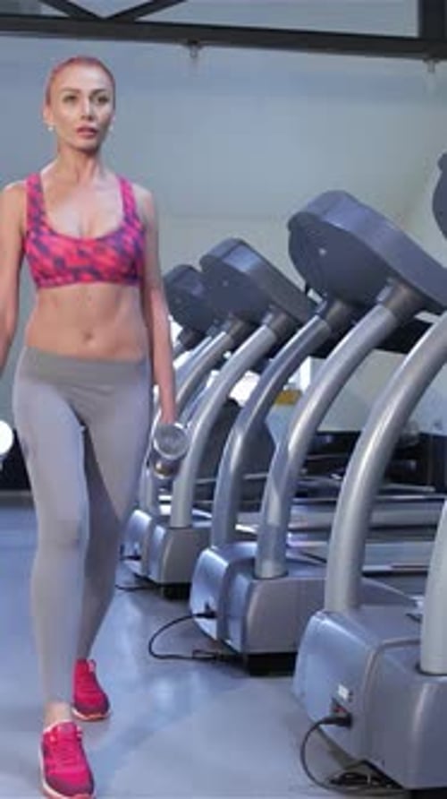 Determined Woman Performs Stepup Exercise with Dumbbells at Fitness Center