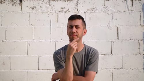 Pensive Man Contemplates Decisions Against White Brick Wall