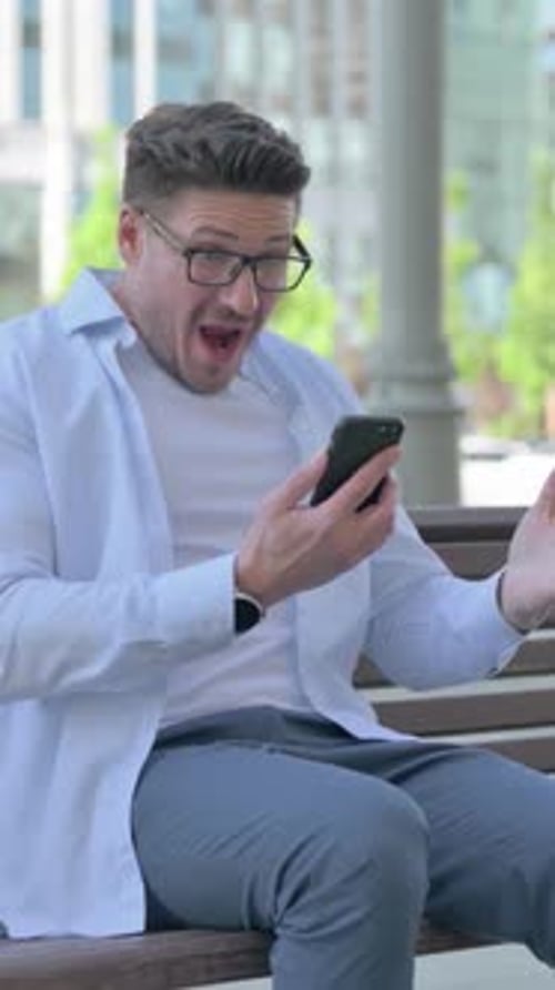 Man Reacting to Message on Phone while Seated