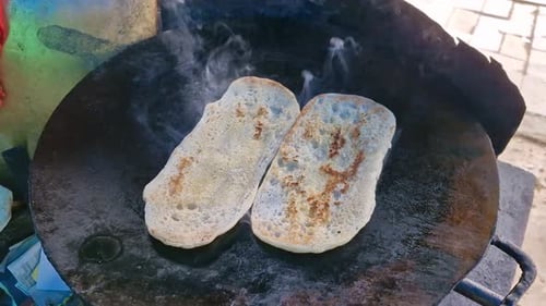 5-7-24 ; Kulcha cuit sur une plaque chauffante, servi avec du chole sur une assiette en carton.