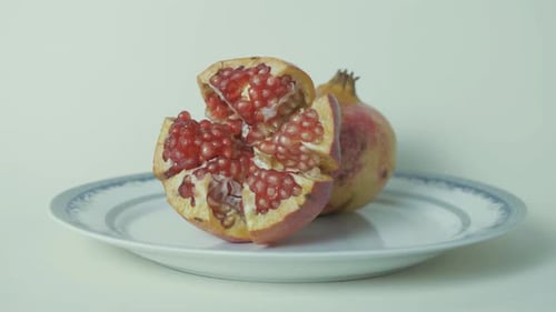 Ripe pomegranate cut open on plate with delicious seeds