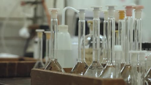 Inclínate hacia abajo para ver un primer plano de los frascos volumétricos en una caja de madera, que contenga una solución transparente.