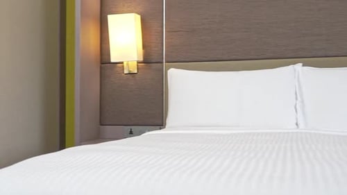 Pan right on the made-up bed with white striped linen and pig pillows in a hotel resort in Miami, Fl