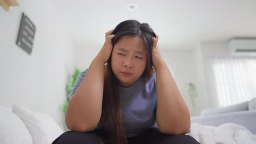 Asian depression plus-size woman holding her head with pain expression.