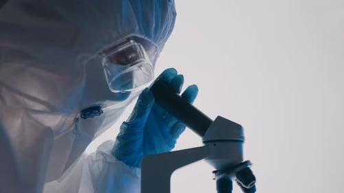 Scientist Examining Specimen Through Microscope in Laboratory