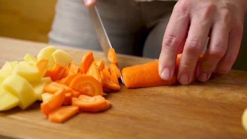 03. Raw peeled carrots are cut into cubes with a knife. Preparation of a vegetable dish.