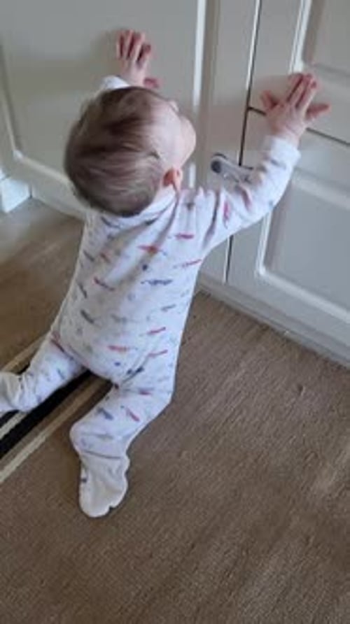 Infant Puling Themself up on Cabinet Indoors