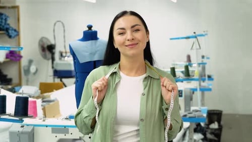 Portrait of a Beautiful Seamstress Carrying a Tape Measure and Working in a Textile Factory