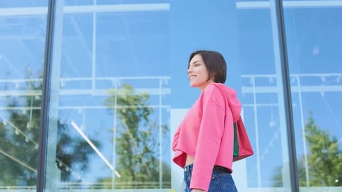 Stylish Woman Walking Past Modern Building with Shopping Bags