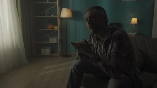 Devastated Lonely Young Man Sits in a Room in the Dark Close Up The Man Thinks Does Not Find a