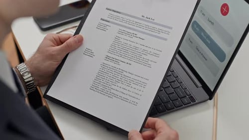Employee Holding CV of Candidate by Laptop at Job Interview