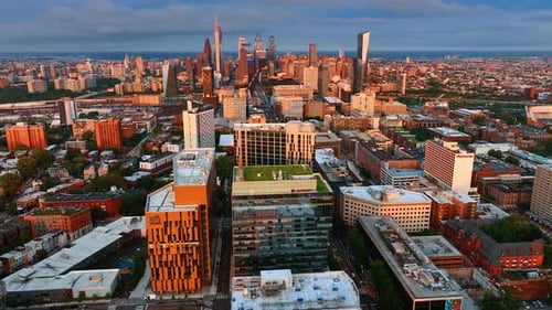 Facades of Philadelphia buildings lit with setting sun. Drone footage above the city panorama