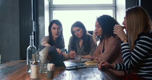 Young Serious Caucasian Female Business Mentor Works with Multiethnic Colleagues at Cafe Points at