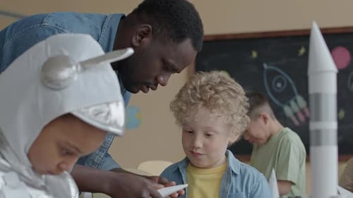 Elementary School Student Making Paper Rockets with Teacher