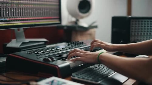 Close up view of man's hands that playing on midi keyboard in the studio