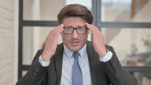 Portrait of Businessman with Headache in Office