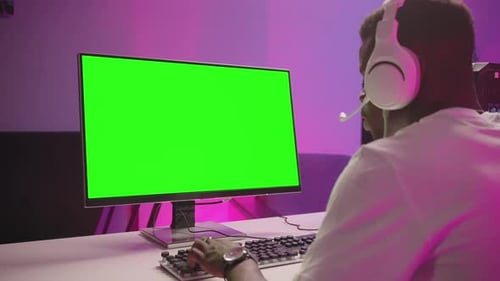 Black Man Playing Computer Game In Room View On Green Screen Through Shoulder Chroma Key Technology