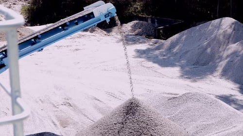 Conveyor belt distributing crushed stone creating mounds in a mining quarry