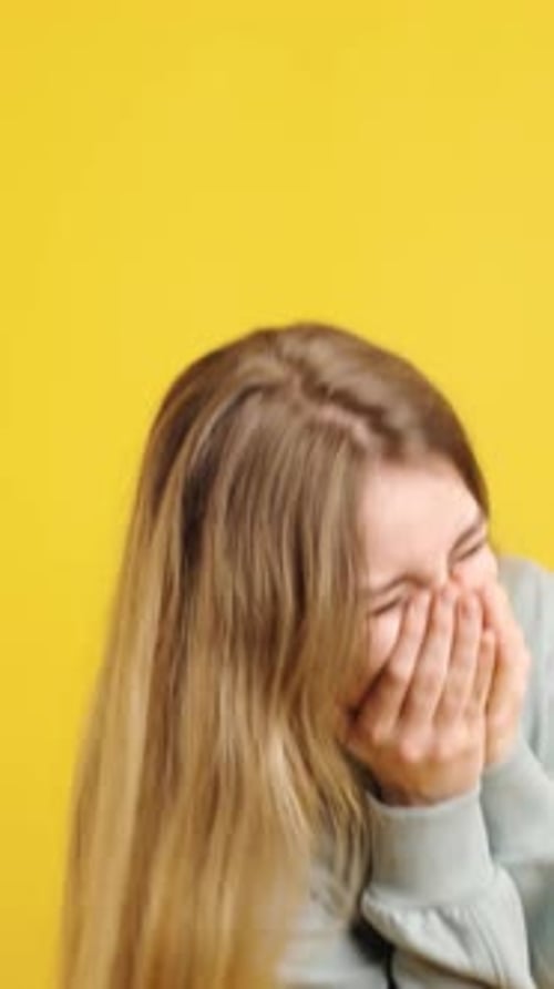 Young Adult Woman Gesturing and Laughing on Yellow Background