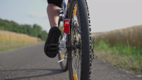 Eine Person radelt mit einem Fahrrad eine Straße entlang, während die Räder eingeschaltet sind