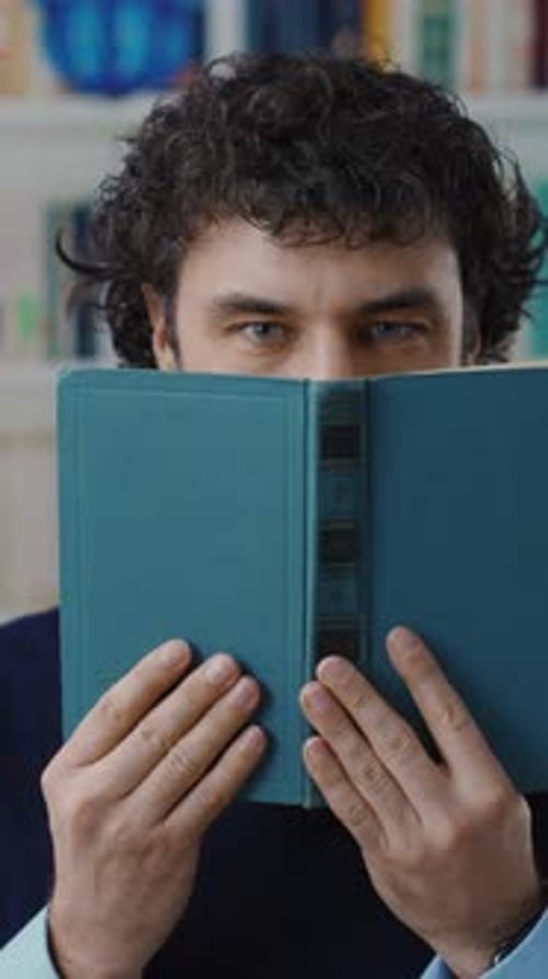 A Person is Hiding Behind a Book in a Comfortably Cozy Setting Inviting Calm and Creativity