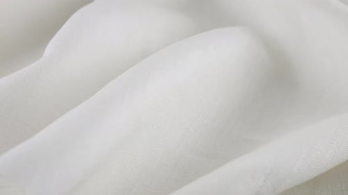 Weiche Falten des weißen Leinenstoffes drehen sich auf der Vitrine. Nahaufnahme des textilen Hintergrunds
.