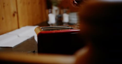 Putting Bread Into Red and Wood Toaster