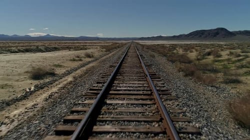 Schnelle, über Kopf zurückgezogene Luftaufnahme gerader Eisenbahnschienen in der Wüste