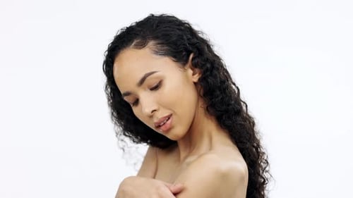 Face, beauty and skincare with a model black woman touching her shoulder in studio on a gray