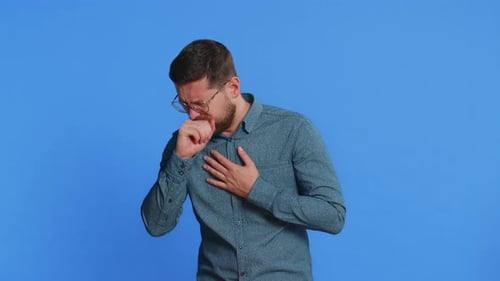 Man with Glasses Coughing into Fist on Blue Background