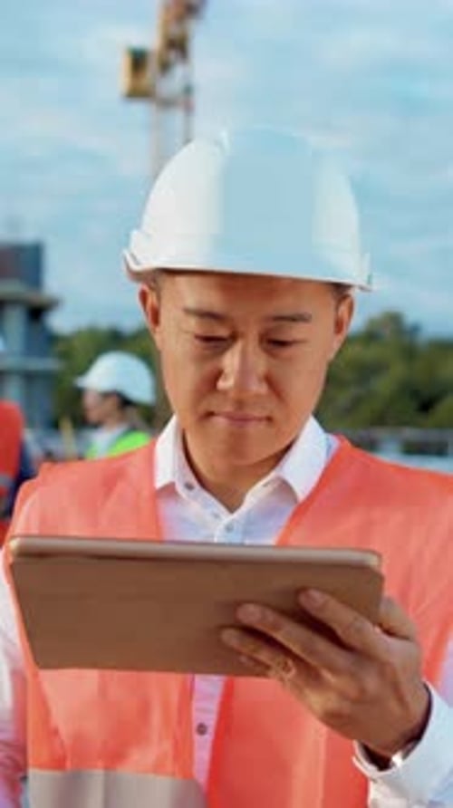 Construction Worker Smiles Holding Tablet on Site