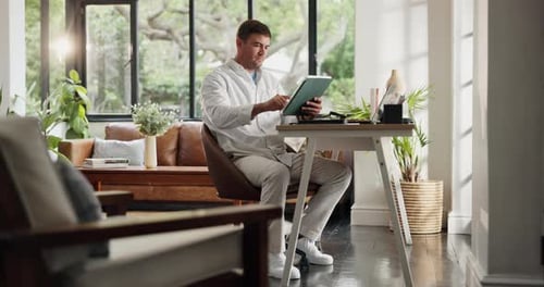 Man Working at Desk Using Tablet in Home Office