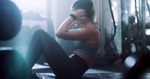 An attractive young sportswoman doing sit ups while working out in a gym