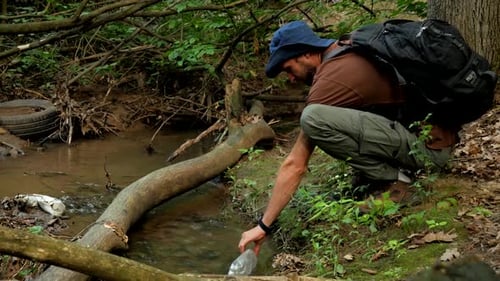 Ranger pick up water into the plastic bottle from the river at the jungle close-up
