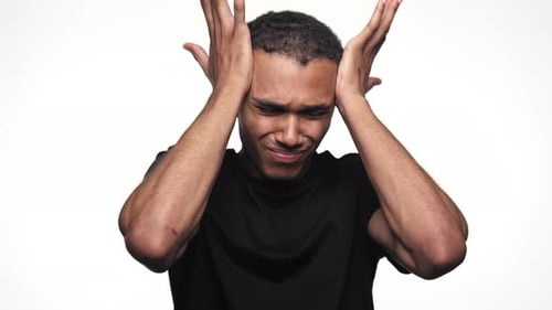 Stressed Young Adult Man Holding Head in Pain