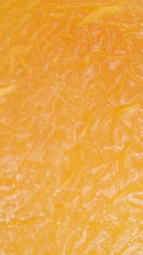 Vertical video. Dried apricot falls onto other apricots, top view, in super slow motion. Macro zoom.
