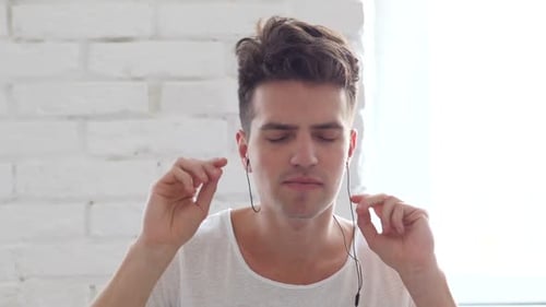 Young Man Enjoying Music with Earbuds, Close Up