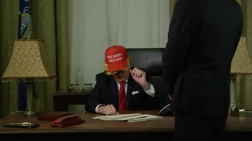 Man in Red Hat Gesturing at Desk