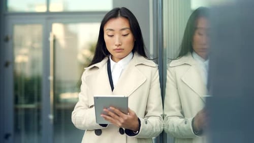Woman Using Tablet Standing Outside Urban Building