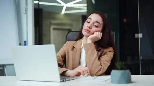 Femme démotivée ayant besoin d'inspiration tout en étant assise avec un ordinateur portable au bureau