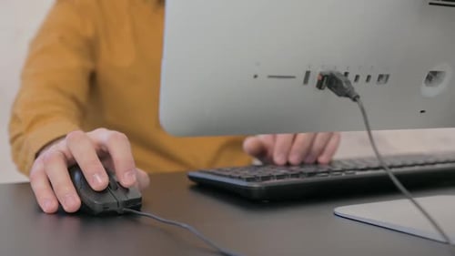 Person Typing and Using Mouse on Computer
