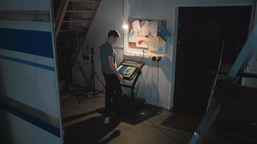 Man Operating Touchscreen Control Panel in Dim Studio Workspace