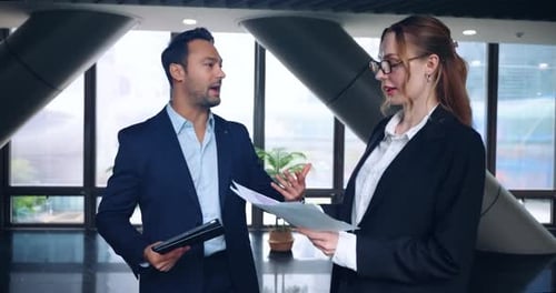 Two business people discussing documents in modern office