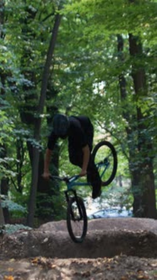 Un cycliste fait des exercices de saut sur terre en écartant les bras sur le vélo