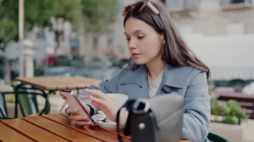 Young Woman Using Smartphone at Outdoor Cafe in the City