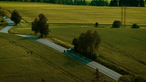 Automobile Cruising on Peaceful Road Surrounded By Green Fields at Sunset Teal Crossover Driving