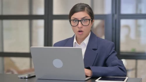 Young Woman Reacts to News on Laptop at Work