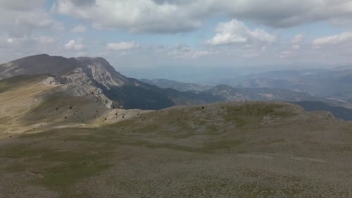 Slow aerial panoramic view of the top of the mountain range, the meadows, and the cliff