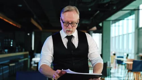 Businessman checking the documents in the office. Man in glasses demonstrates one of the charts.