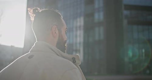 Young Man with Stylish Trendy Hairstyle and Beard in Casual Clothes Walking Down the Street in Urban